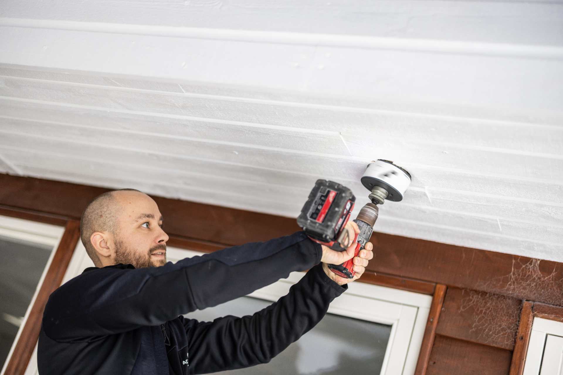 Elektriker i Roskilde der borer et hul i et hvidt loft.